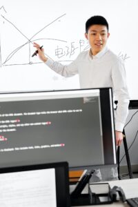 A Man in Smart Casual Attire Talking beside an Interactive Whiteboard